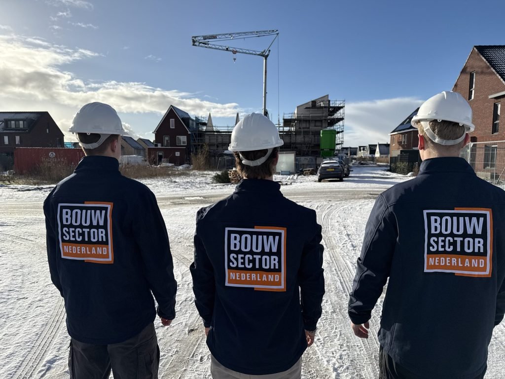 Drie vakmensen van Bouwsector Nederland met witte helm voor nieuwbouwwoningen in aanbouw en een bouwkraan